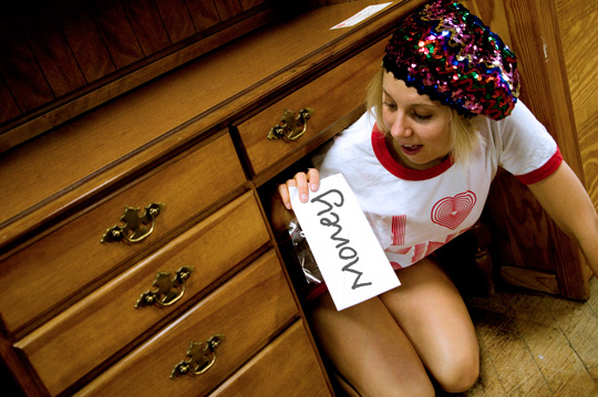 girl under a desk in a thrift store finding an envelope of money