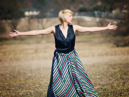 woman wears a vintage style striped skirt in a field